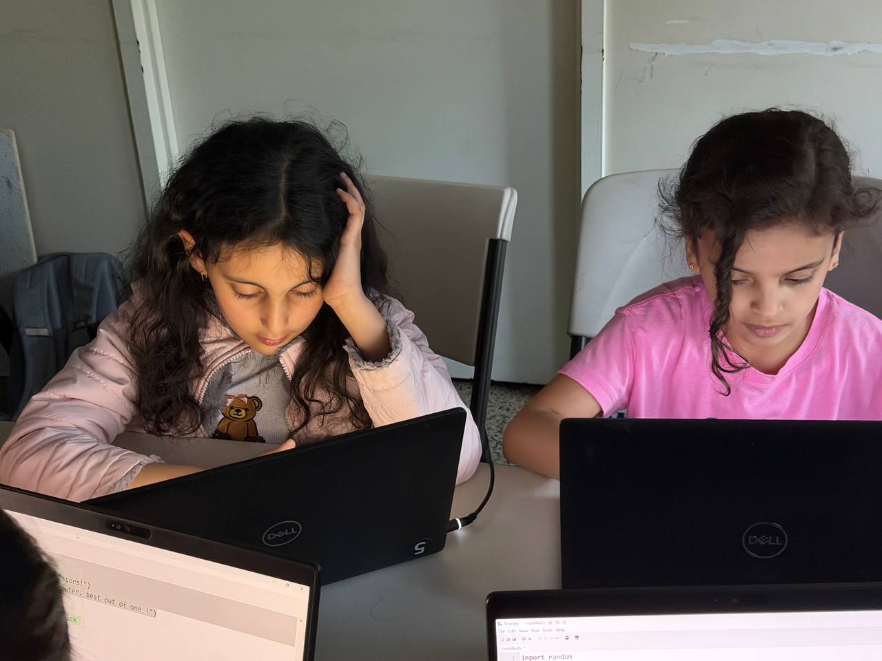 Two students focused on laptops during a small-group coding lesson