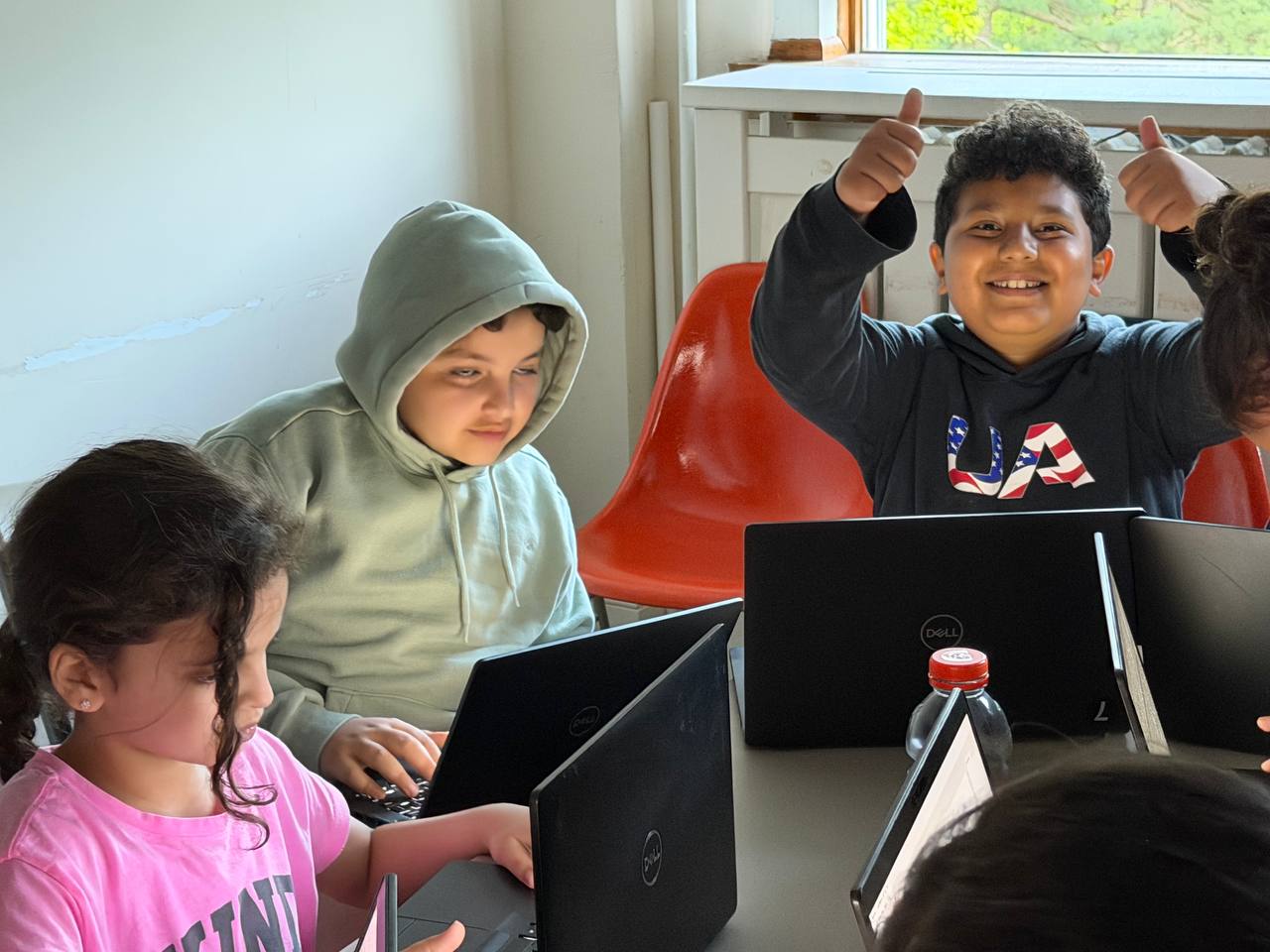Students working together in a small-group coding class with one student giving thumbs up